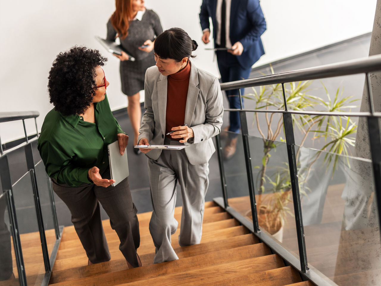 A group of business professionals converses on a modern staircase in a stylish office, emphasizing teamwork and collaboration.